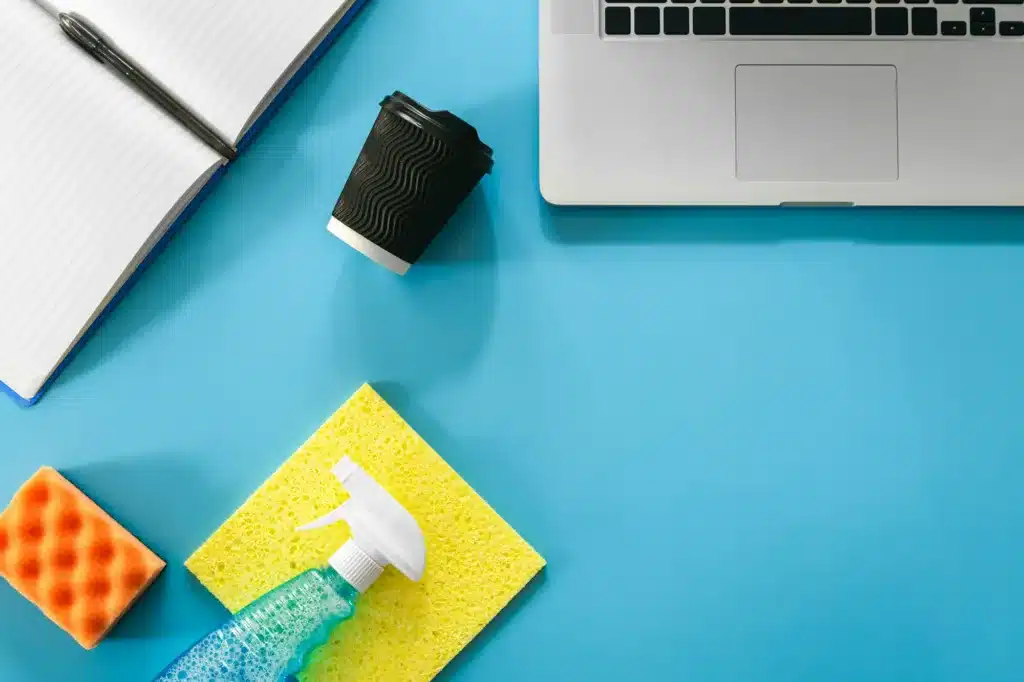Workplace with laptop and cleaning products, flat lay.